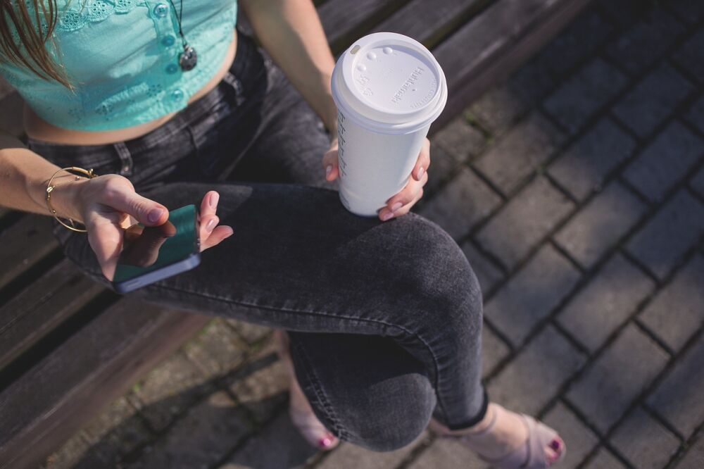 Een vrouw die haar koffie via de smartphone contactloos betaalt